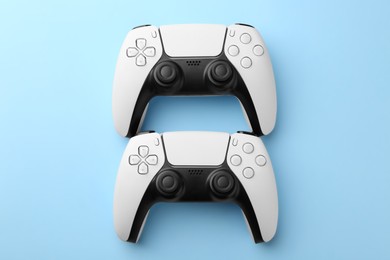 Wireless game controllers on light blue background, flat lay