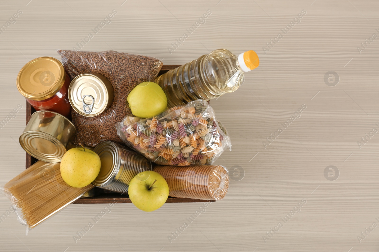 Photo of Donation box with food on wooden table, top view. Space for text