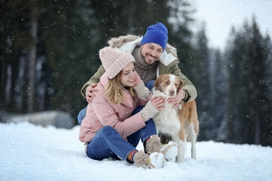 Cute couple with dog near forest. Winter vacation