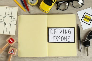 Photo of Flat lay composition with workbook for driving lessons and road signs  on wooden background. Passing license exam
