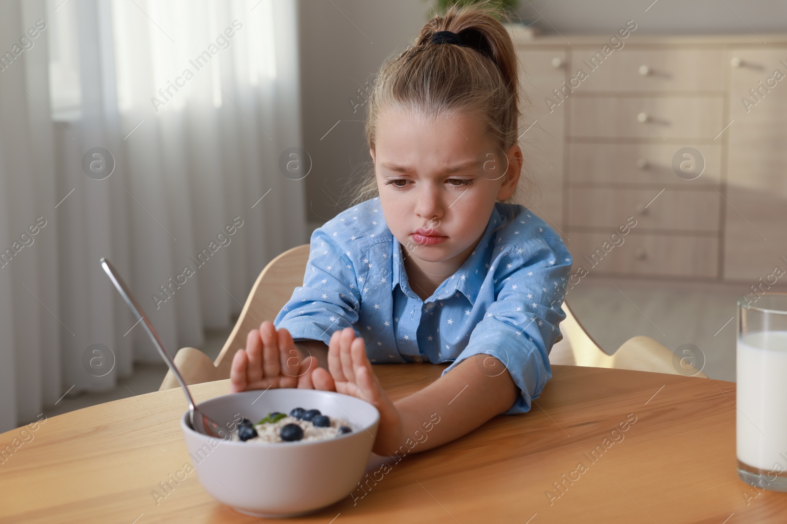 Photo of Cute little girl refusing to eat her breakfast at home