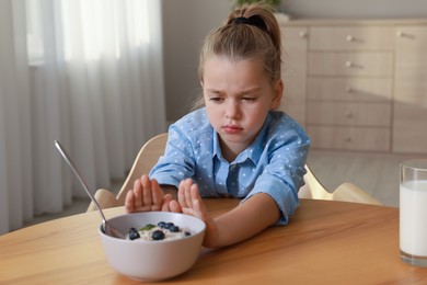 Cute little girl refusing to eat her breakfast at home