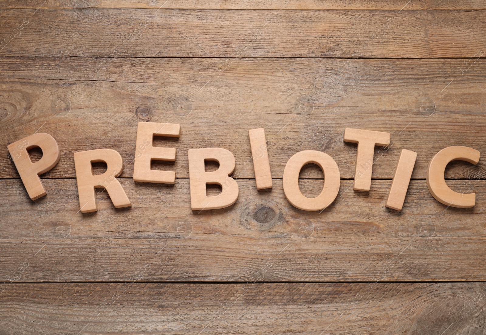 Photo of Word Prebiotic made of wooden letters on table, flat lay