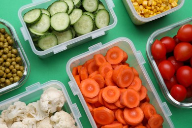 Plastic containers with different fresh products on green background, flat lay