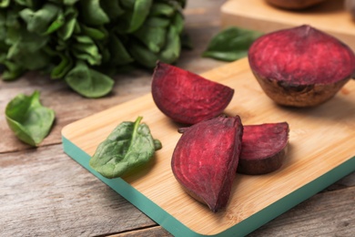 Photo of Wooden board with cut beet on table