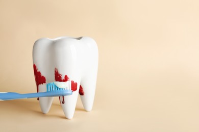 Photo of Tooth model, brush and blood in toothpaste foam on beige background, space for text. Gum problems