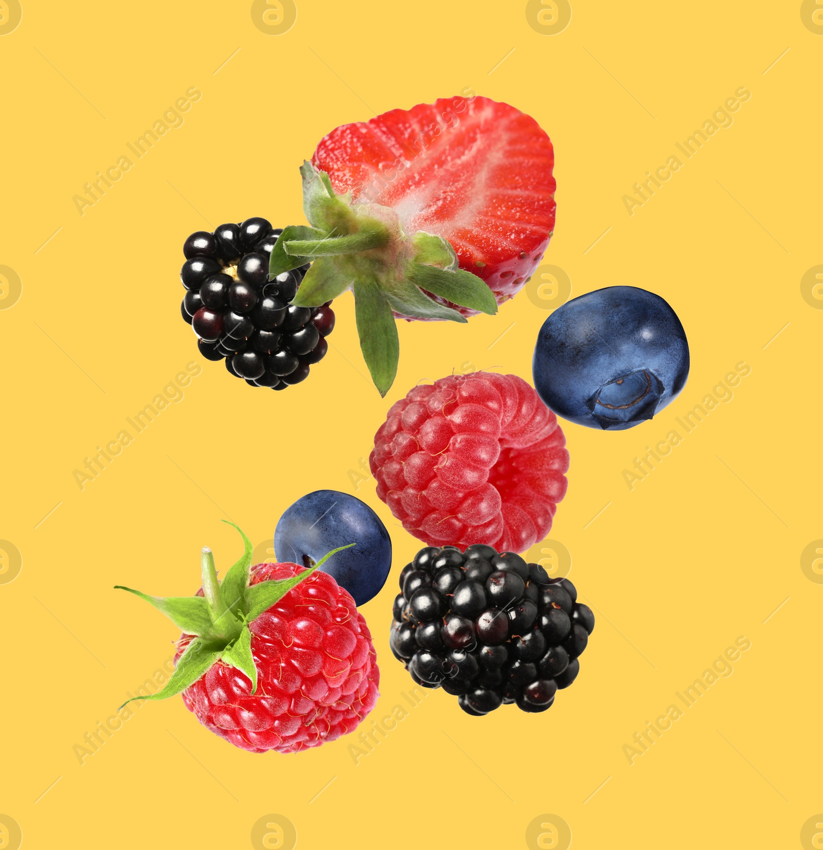 Image of Many different fresh berries falling on golden background