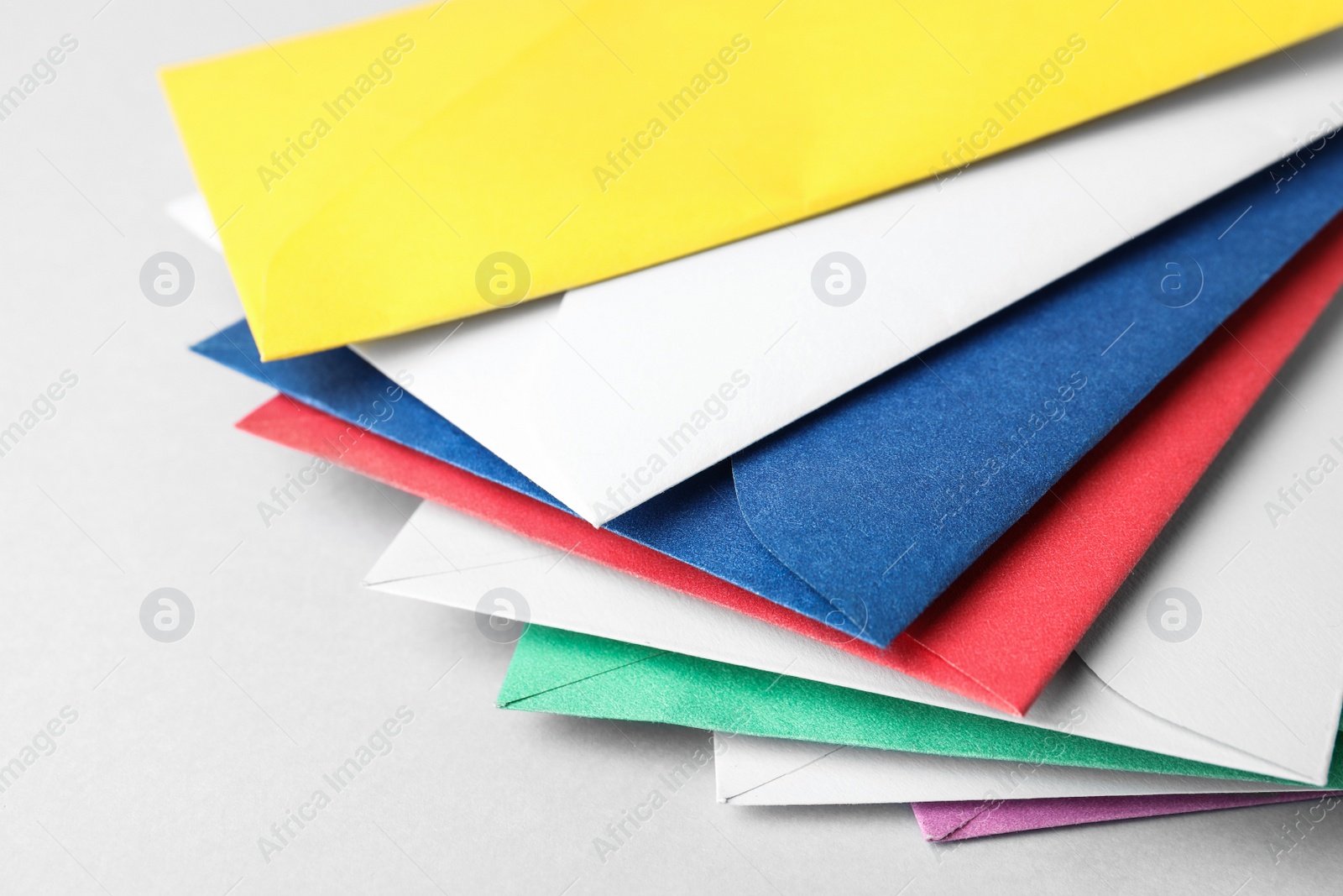 Photo of Colorful paper envelopes on light background, closeup