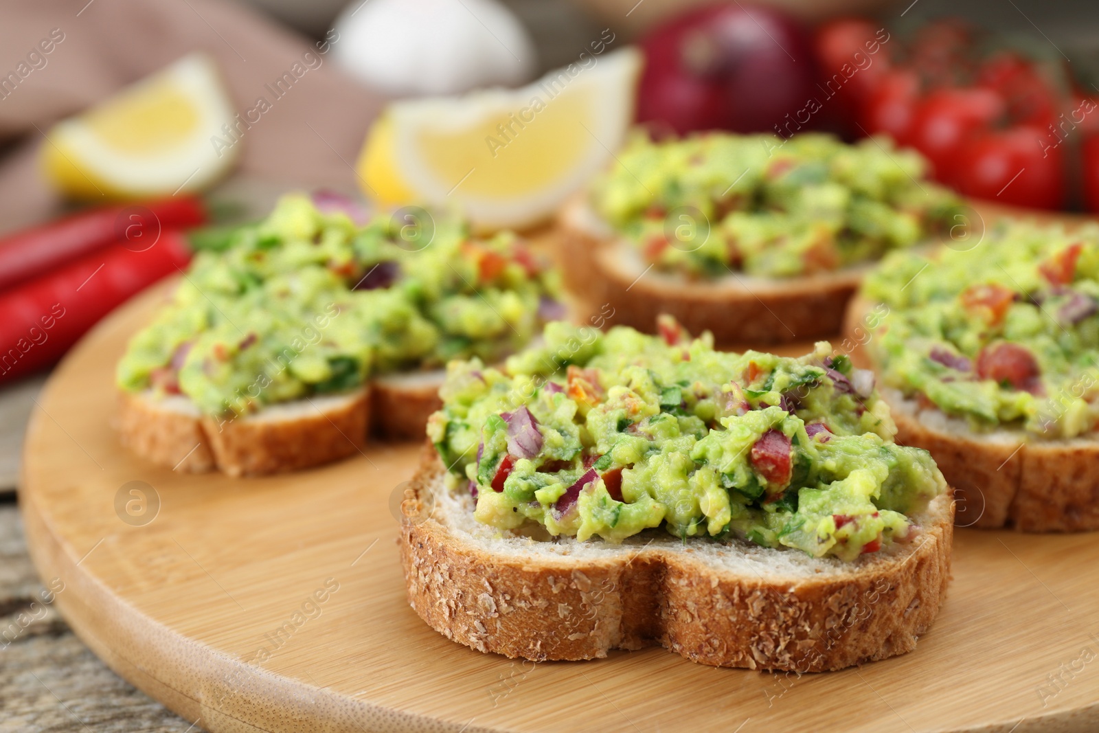 Photo of Slices of bread with tasty guacamole on wooden table, closeup