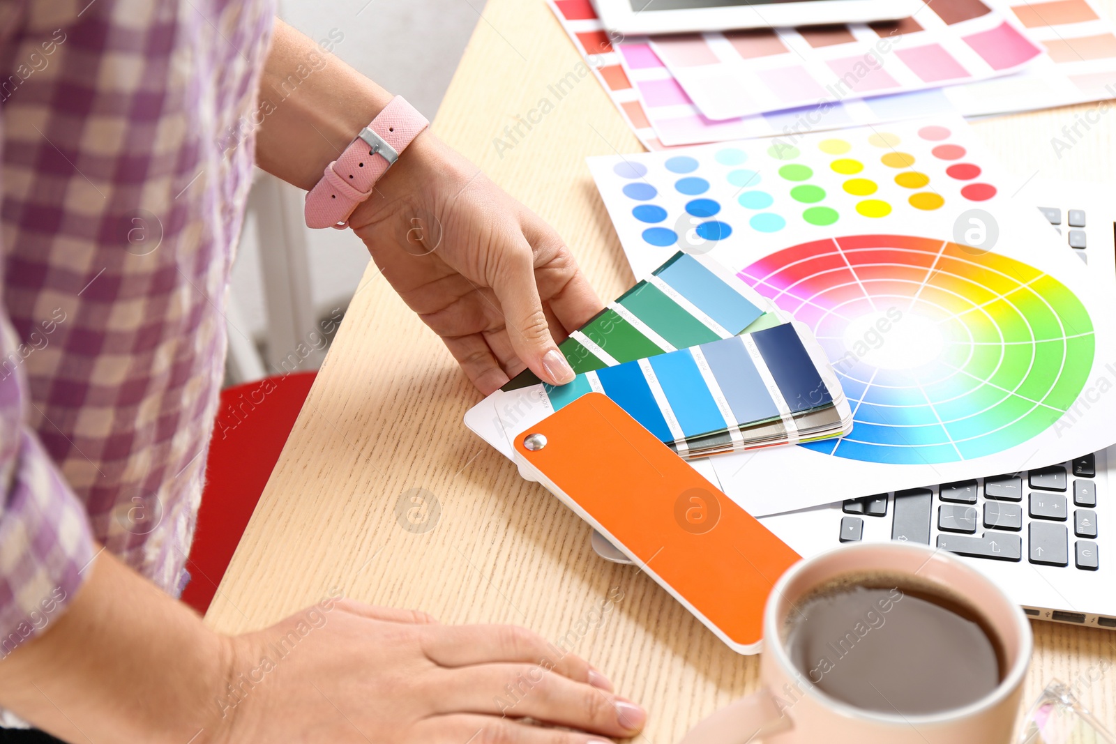 Photo of Woman working with palette samples at wooden table, closeup