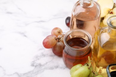 Photo of Different types of vinegar and ingredients on light marble table, closeup. Space for text