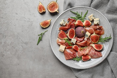 Photo of Plate with figs, prosciutto and cheese on light table, top view. Space for text