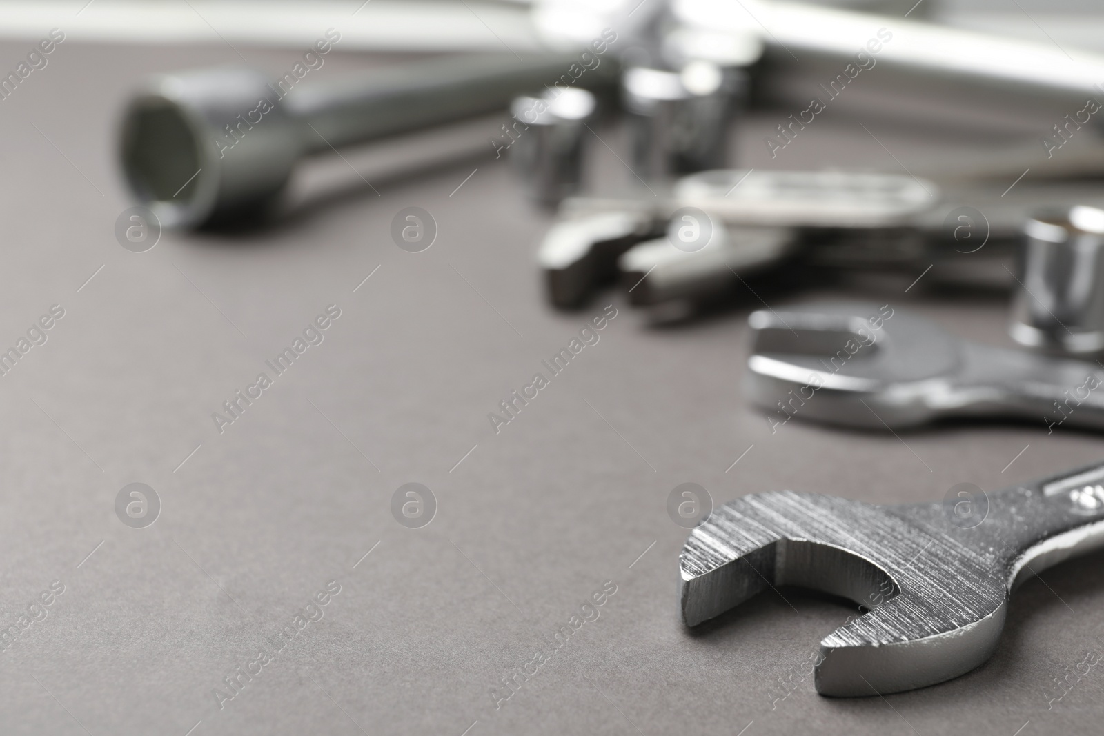 Photo of Auto mechanic's tools on grey background, closeup. Space for text