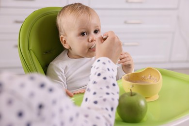 Mother feeding her cute little baby with healthy food at home