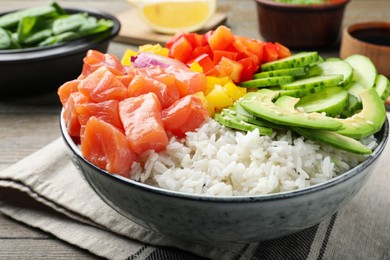 Delicious poke bowl with salmon and vegetables served on table, closeup