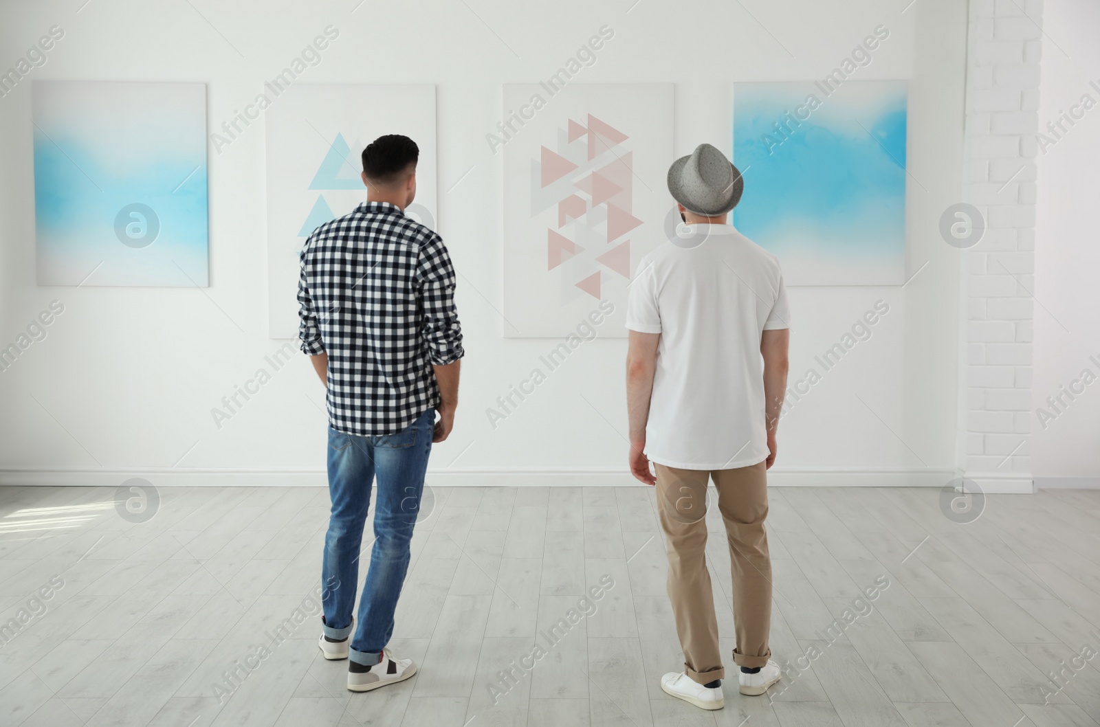 Photo of Men at exhibition in art gallery, back view