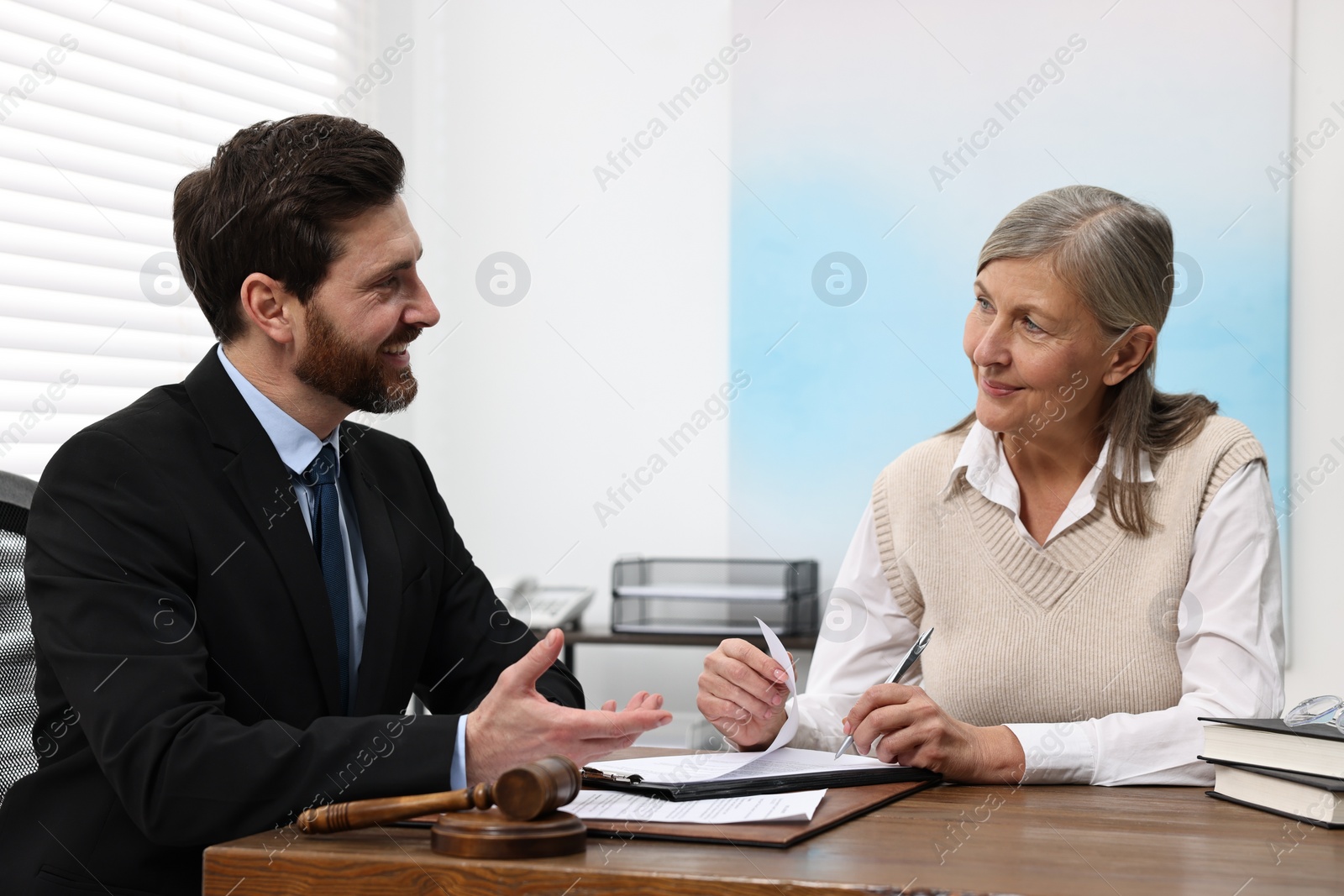 Photo of Senior woman signing document in lawyer's office