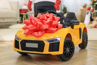 Photo of Children's electric toy car with red bow in room decorated for Christmas