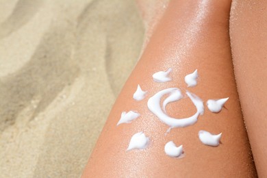 Photo of Sun drawn with sunscreen on woman's leg at beach, closeup. Space for text