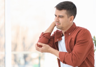 Photo of Young man suffering from elbow pain at home