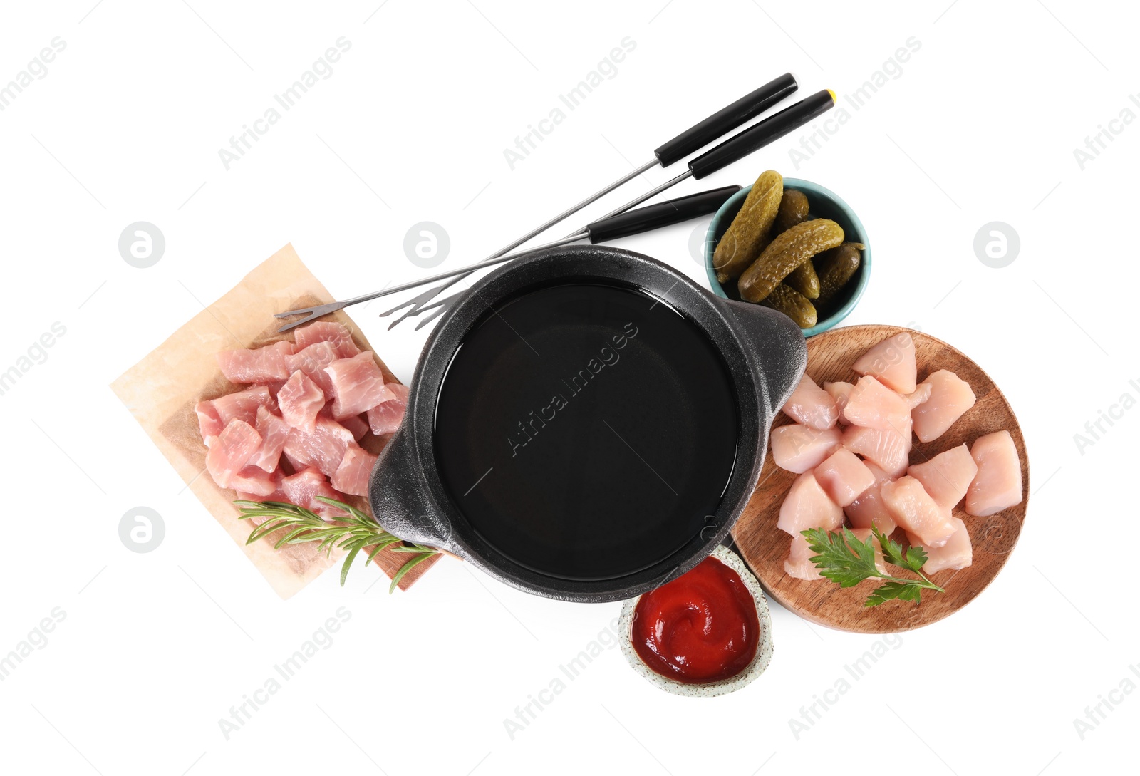 Photo of Fondue pot with oil, forks, raw meat pieces and other products isolated on white, top view