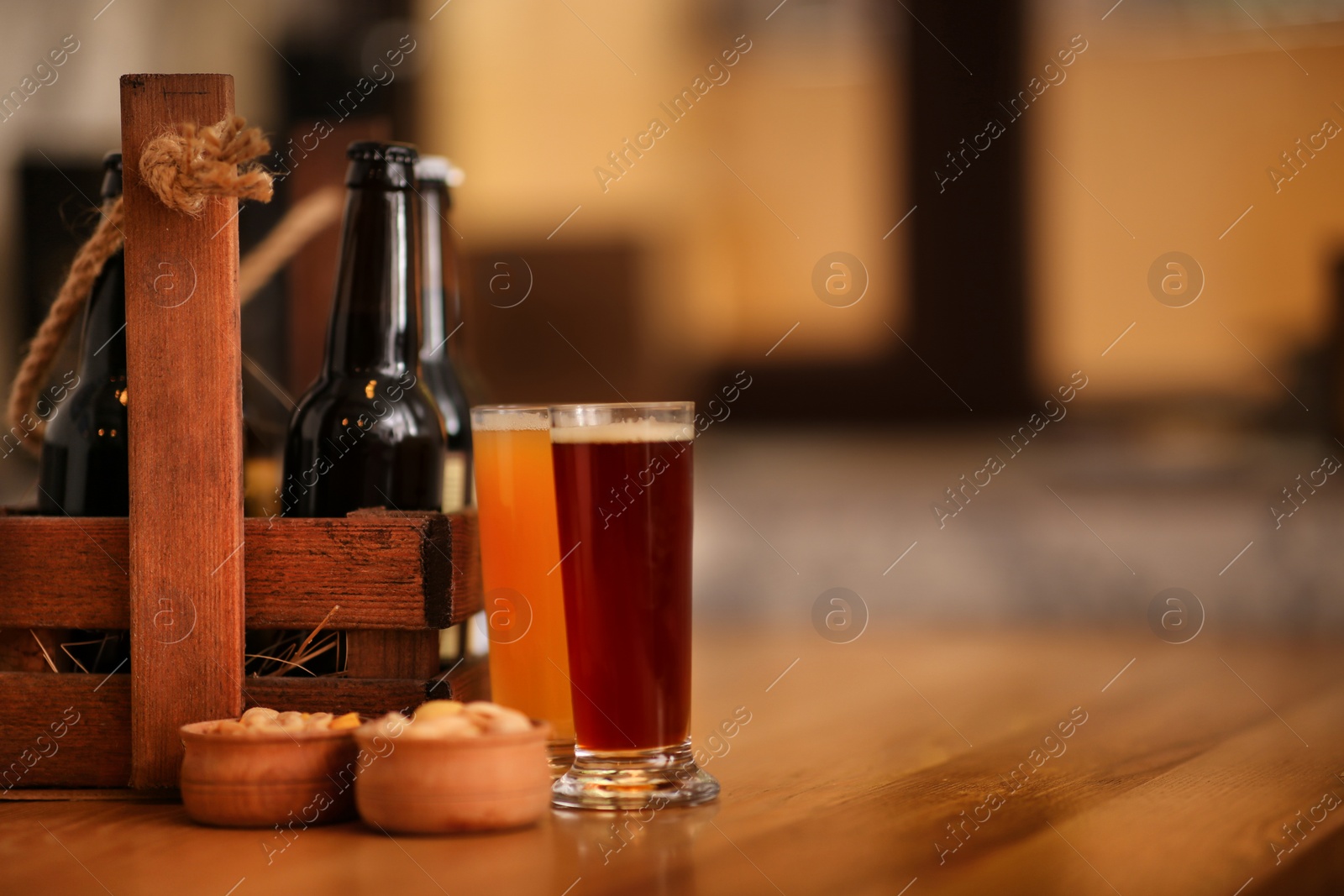 Photo of Different beers served with peanuts on wooden table, space for text