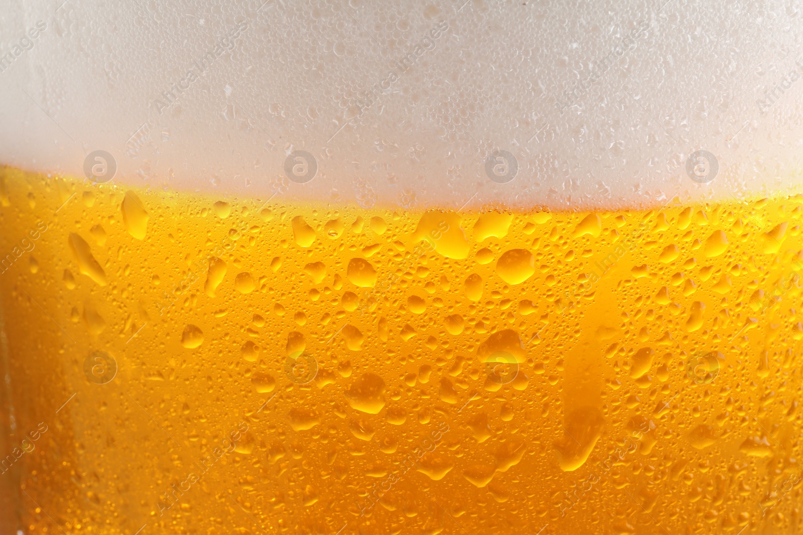 Photo of Glass of tasty cold beer with foam and condensation drops as background, closeup