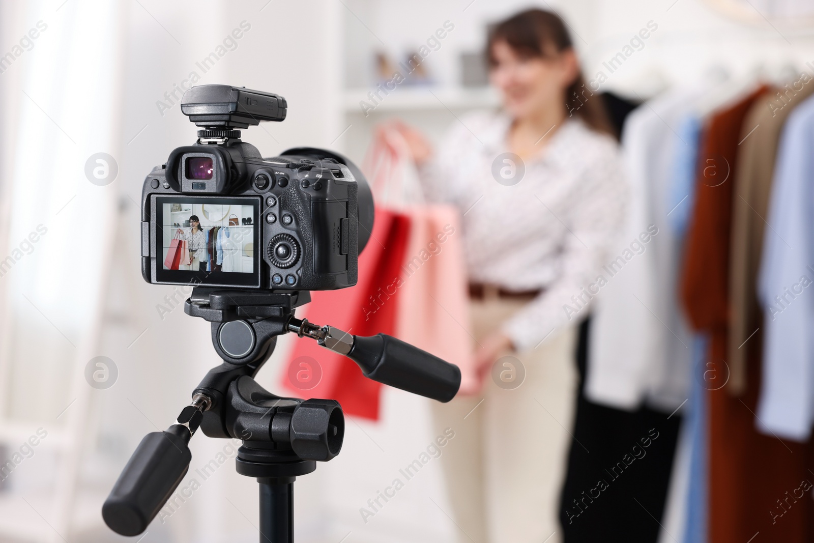 Photo of Fashion blogger with shopping bags recording video at home, focus on camera