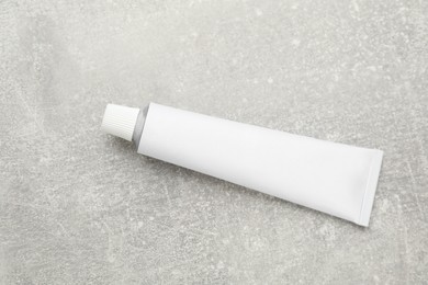 Photo of Blank white tube of ointment on light grey table, top view. Space for text