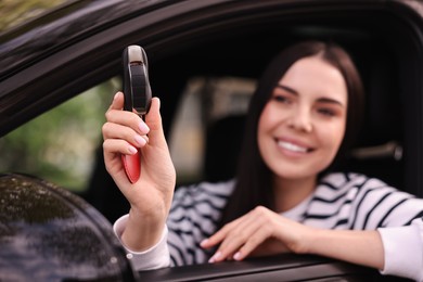 Photo of Woman holding car flip key inside her vehicle, selective focus