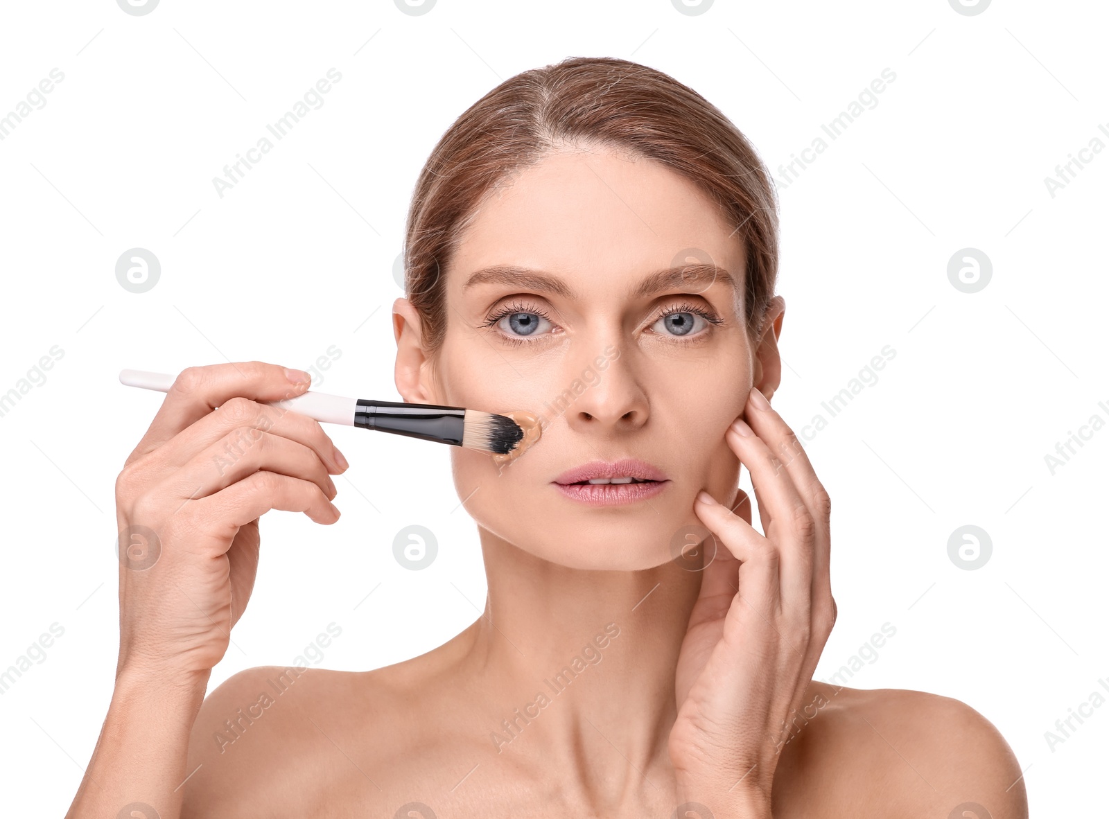 Photo of Woman applying foundation on face with brush against white background