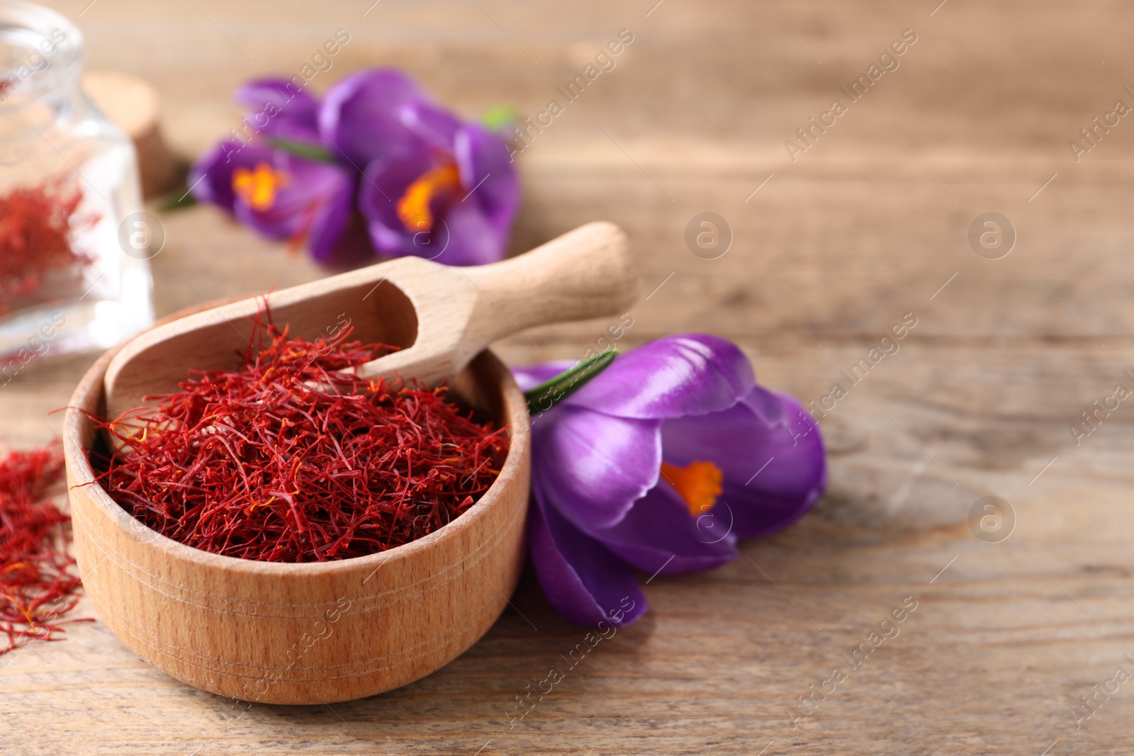 Photo of Dried saffron and crocus flowers on wooden table. Space for text