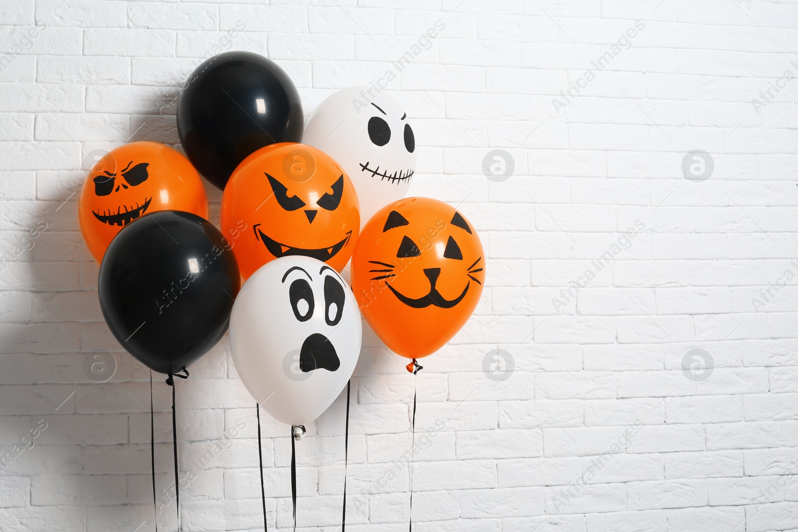 Photo of Color balloons for Halloween party against white brick wall. Space for text