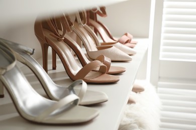 Photo of Different stylish women's shoes on shelf in dressing room, closeup