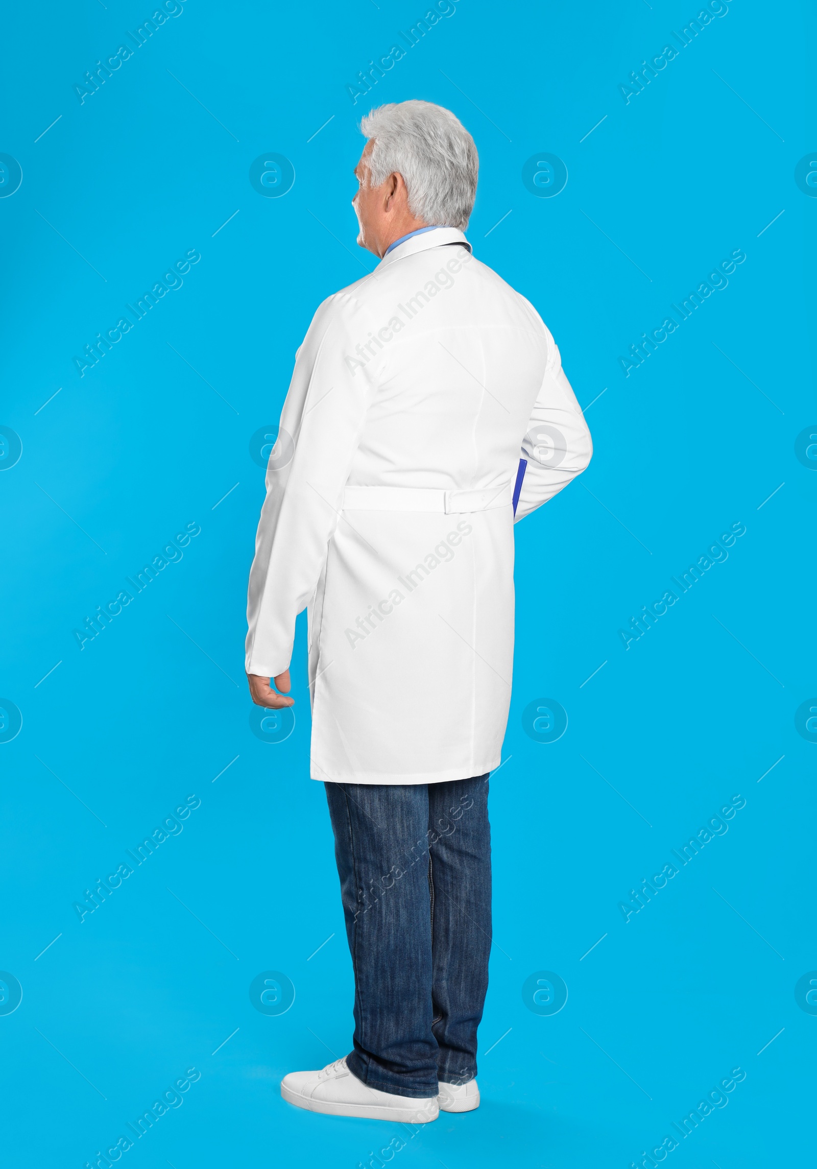 Photo of Senior doctor on light blue background, back view