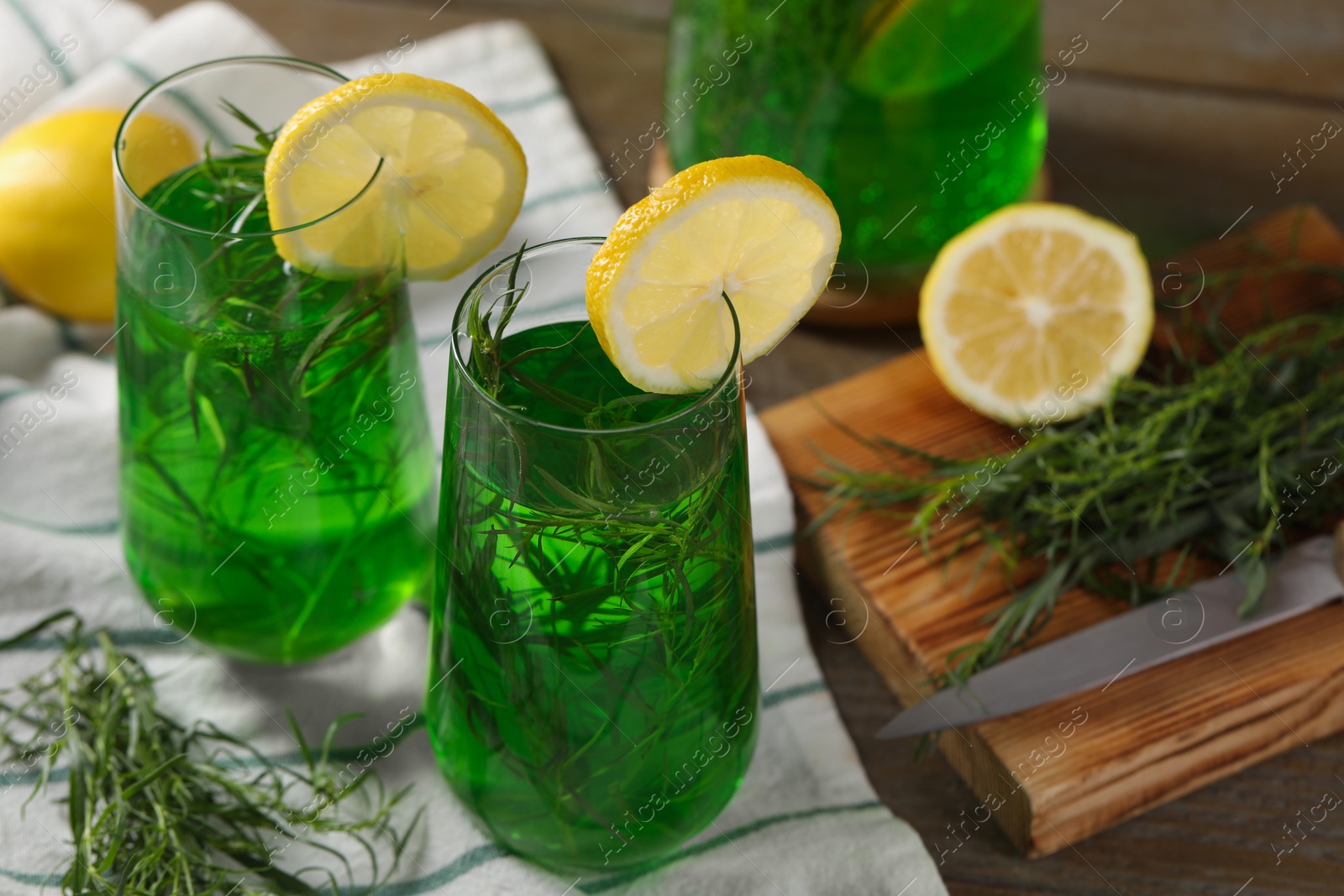 Photo of Glasses of refreshing tarragon drink with lemon slices on table