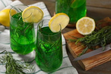 Photo of Glasses of refreshing tarragon drink with lemon slices on table