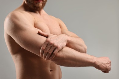 Man with muscular body on light grey background, closeup