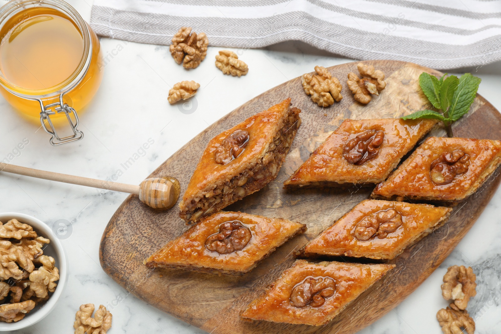 Photo of Delicious honey baklava with walnuts on white marble table, flat lay