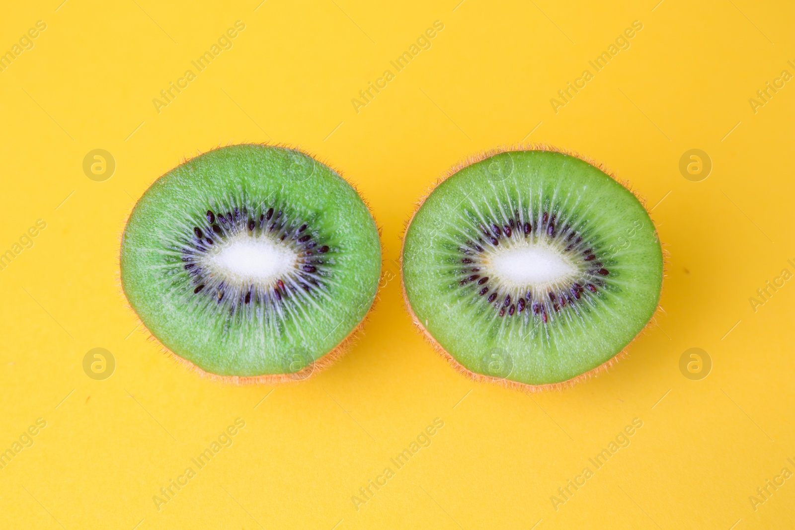 Photo of Cut fresh ripe kiwis on yellow background, flat lay