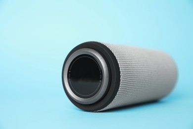 Photo of One portable bluetooth speaker on light blue background, closeup with space for text. Audio equipment