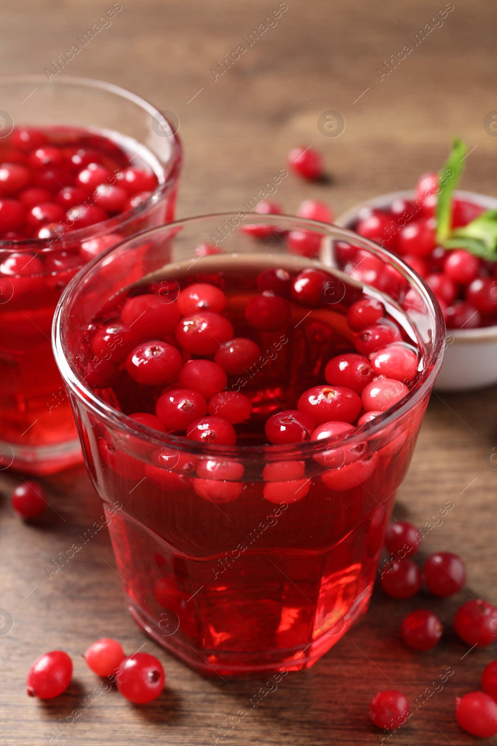 Photo of Tasty cranberry juice in glasses and fresh berries on wooden table, closeup