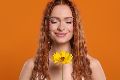 Photo of Beautiful young hippie woman with sunflower on orange background