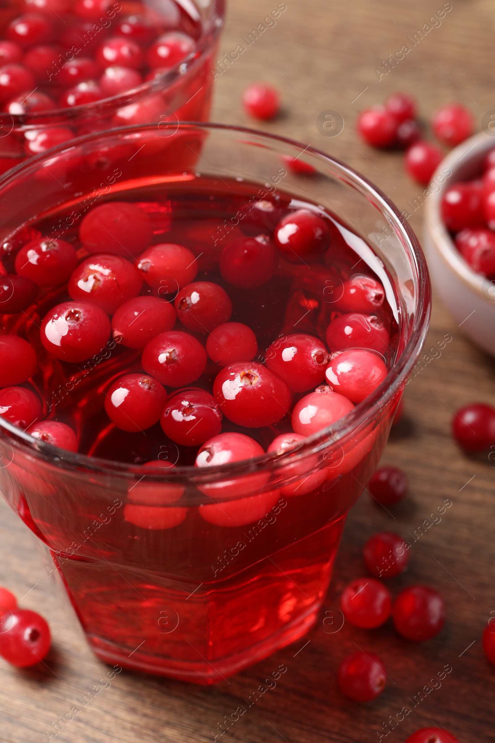 Photo of Tasty cranberry juice in glasses and fresh berries on wooden table, closeup