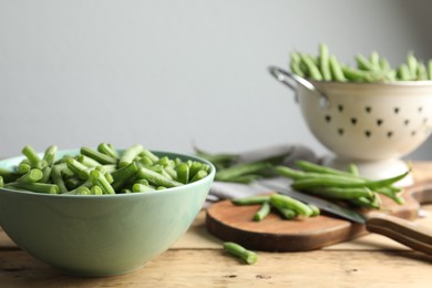 Fresh green beans in bowl on wooden table, closeup. Space for text