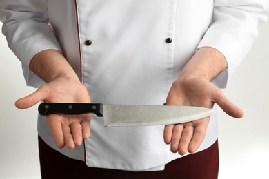 Man holding chef's knife on white background, closeup