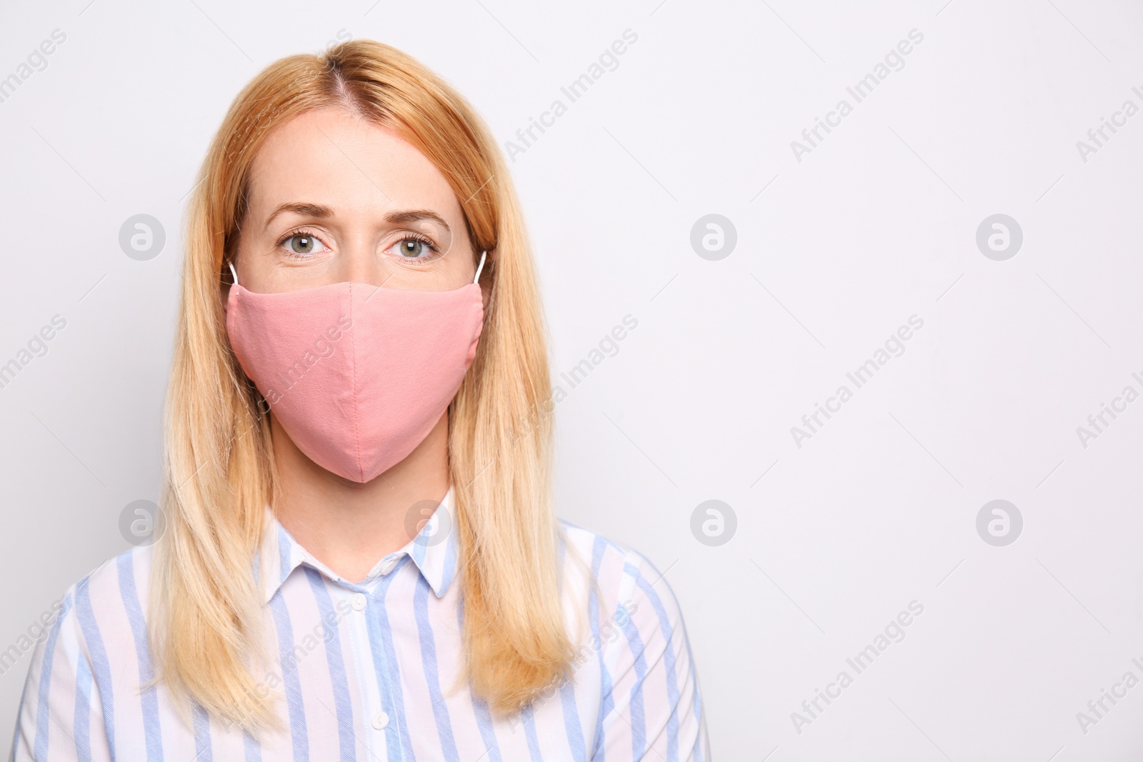 Photo of Woman wearing handmade cloth mask on white background, space for text. Personal protective equipment during COVID-19 pandemic