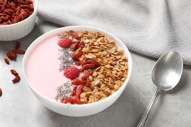 Photo of Smoothie bowl with goji berries and spoon on light grey table