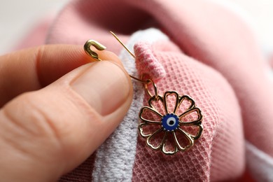Photo of Woman pinning evil eye amulet on clothing, closeup