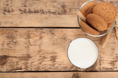 Photo of Glass of milk and oatmeal cookies on wooden table. Fresh dairy product